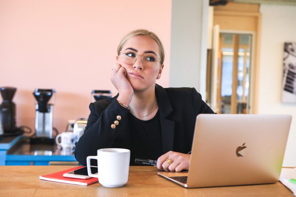 Une femme au travail devant son PC réfléchit à comment réussir sa reconversion professionnelle